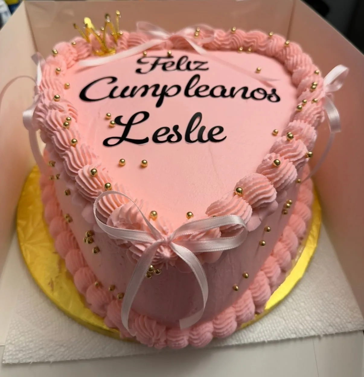 Pink heart-shaped cake piped with rosette borders and gold pearls, with a script name plaque on top