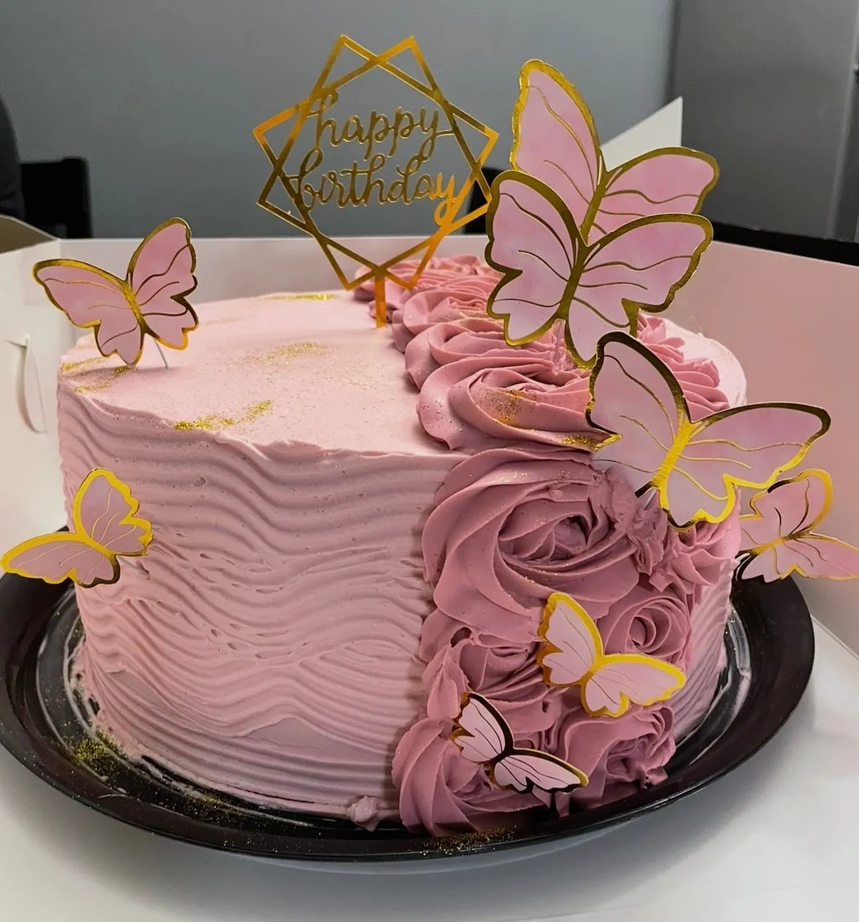 Pink textured buttercream cake with a rosette panel and gold butterfly toppers