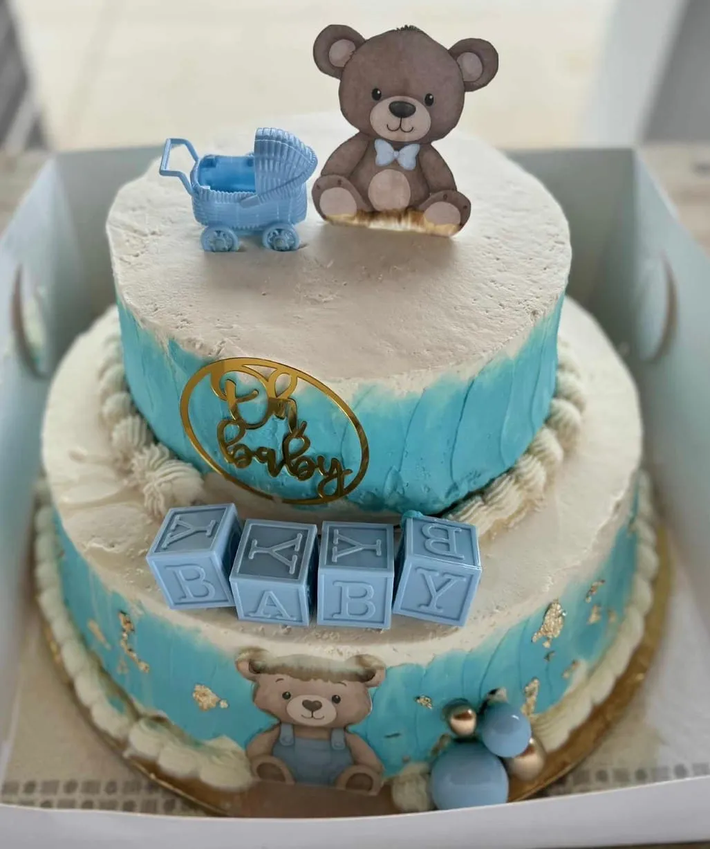 Baby-shower cake in blue and white with teddy bears, a toy stroller, and stacked 'baby' blocks